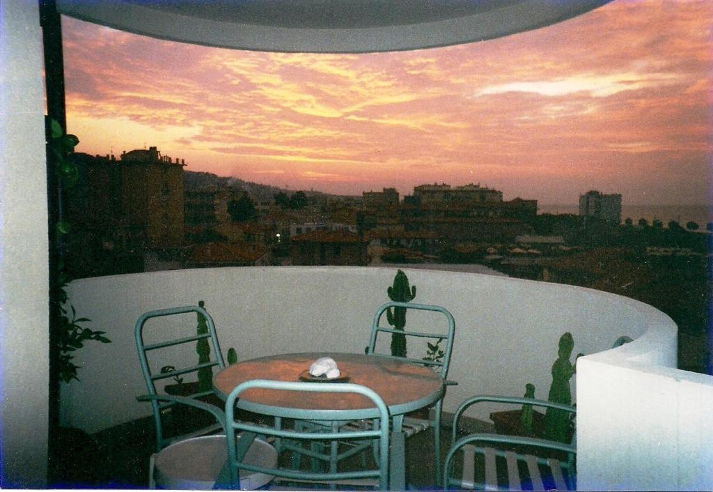 a table and chairs on a balcony with a sunset at Appartamento - terrazzo vivibile vista mare, wi-fi gratuito in Vallecrosia