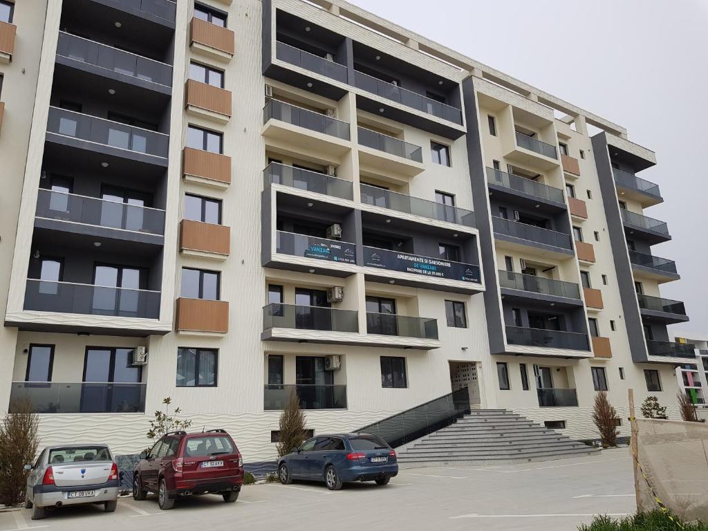 a large apartment building with cars parked in a parking lot at Apartament Ana Navodari Mamaia Nord in Mamaia Nord
