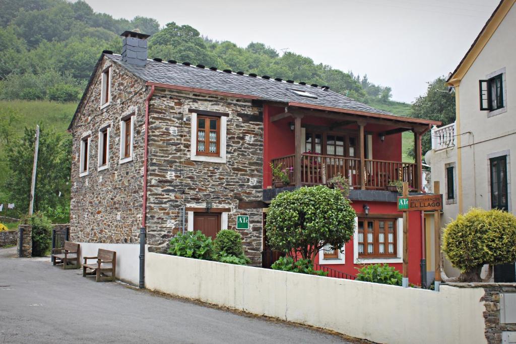 uma casa de pedra com uma fachada vermelha em Apartamentos El Llago em Boal