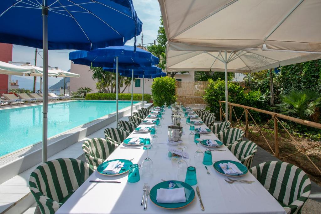 a long table with chairs and umbrellas next to a pool at Palatium Mari in Capri
