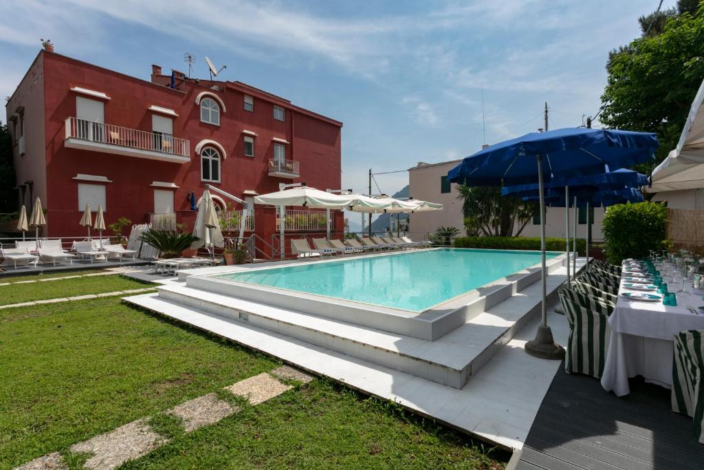 a pool with tables and umbrellas next to a building at Palatium Mari in Capri