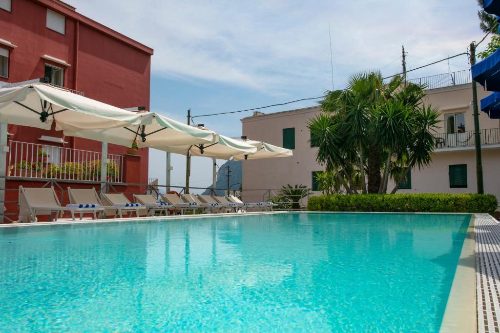 a swimming pool with chairs and umbrellas next to a building at Palatium Mari in Capri