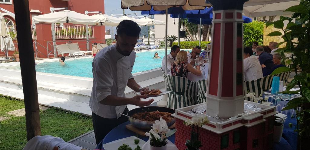 a man holding a plate of food near a pool at Palatium Mari in Capri
