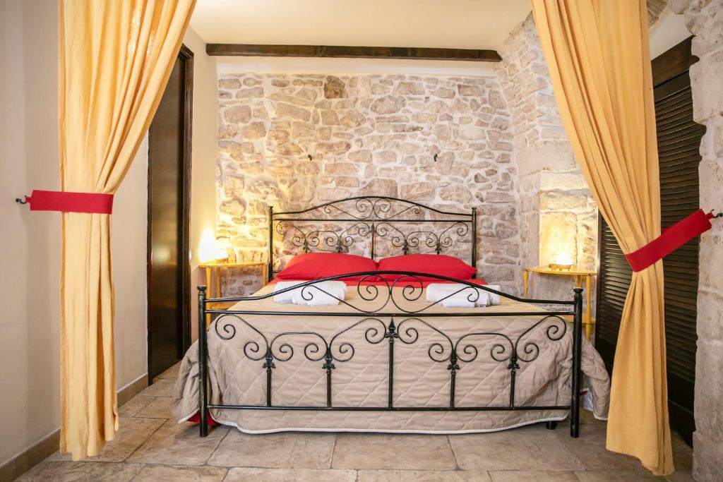 un letto con cuscini rossi in una stanza con parete in pietra di La Casa di Vale a Martina Franca