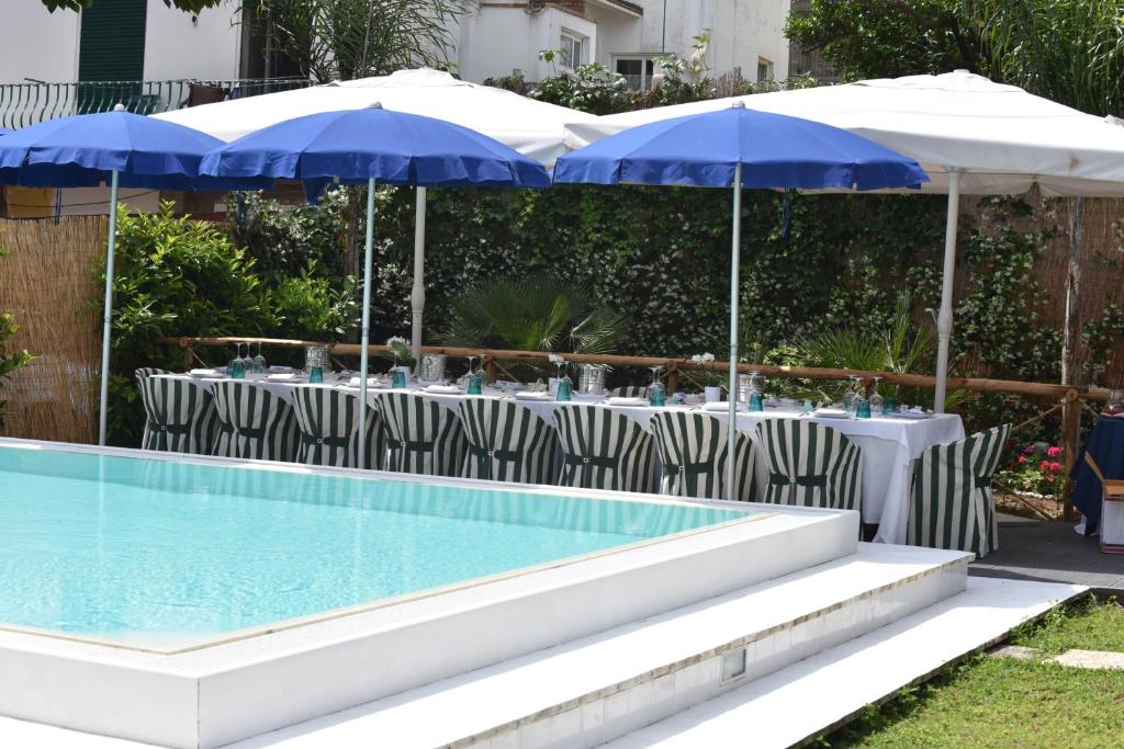 a pool with tables with umbrellas and chairs next to at Palatium Mari in Capri