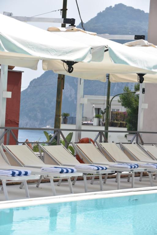 a group of chairs and umbrellas next to a swimming pool at Palatium Mari in Capri