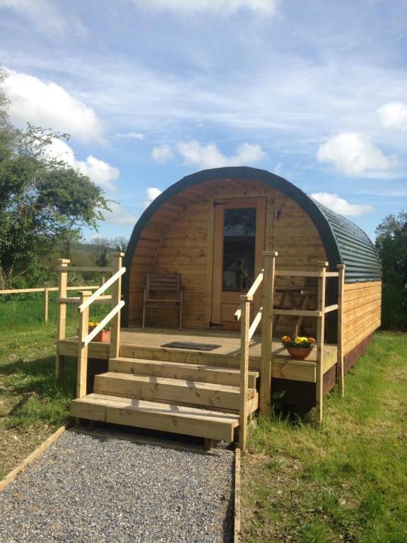 eine Holzhütte mit einer Veranda und einer Treppe im Gras in der Unterkunft Carrigeen Glamping in Kilkenny