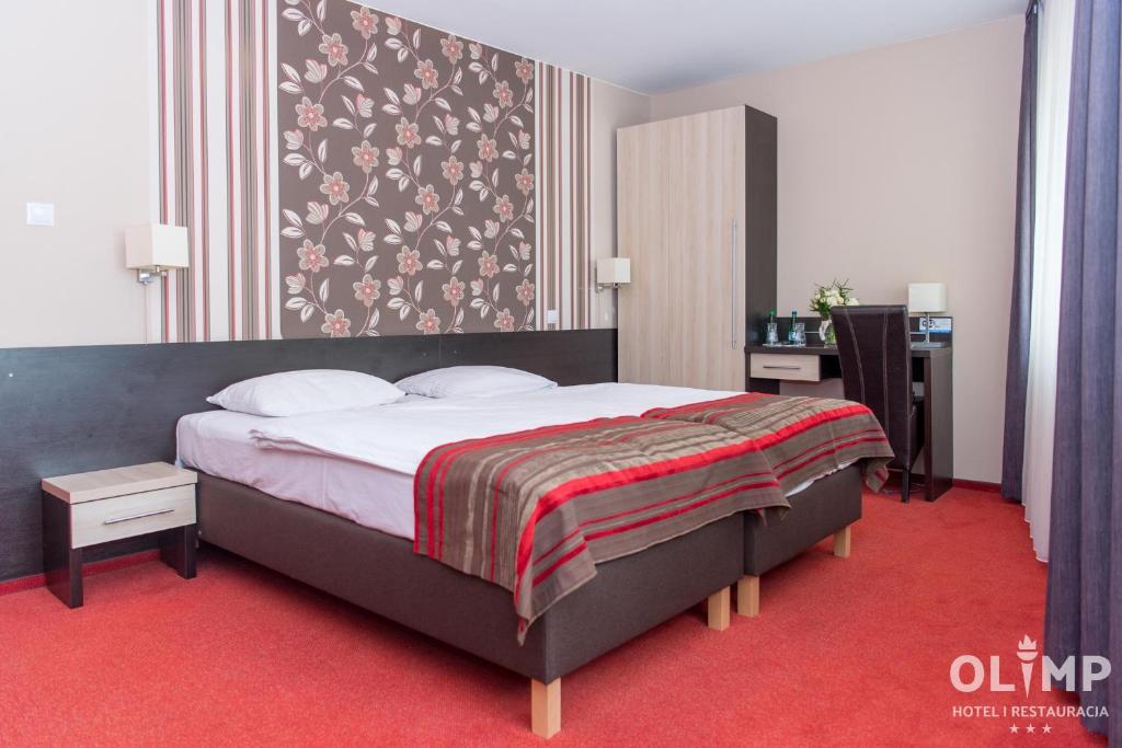 a bedroom with a large bed with a red carpet at Hotel Olimp in Prudnik