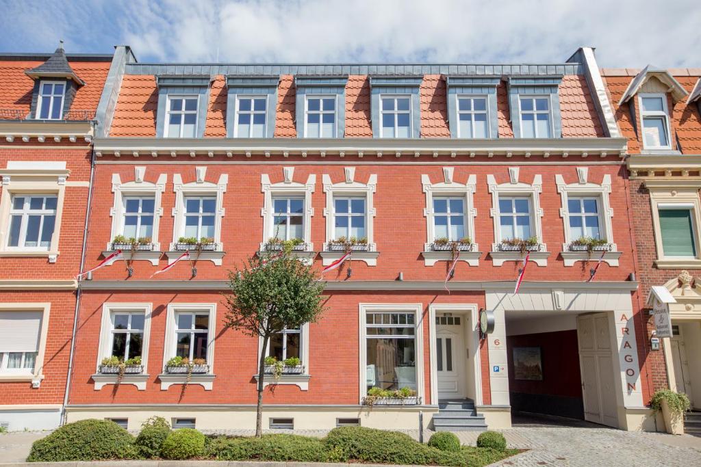 a large red brick building with white windows at Aragon - Hotel - Garni in Tangermünde