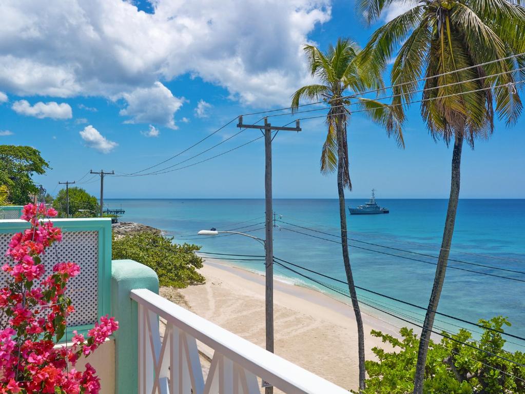 a balcony with a beach and palm trees at Coral Sands & Carib Edge, AC beach condos in Saint Peter