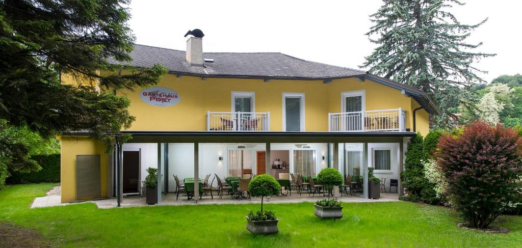 ein gelbes Haus mit Tischen und Stühlen im Hof in der Unterkunft Gästehaus Wrann in Velden am Wörthersee