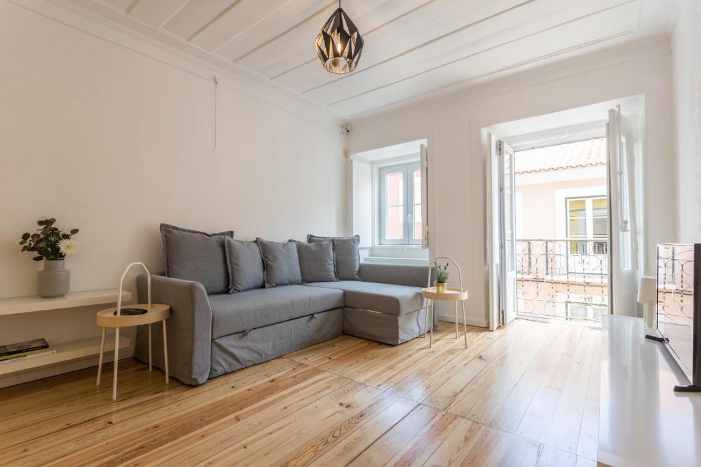 a living room with a gray couch and wooden floors at FLH Príncipe Real Bright Apartment in Lisbon