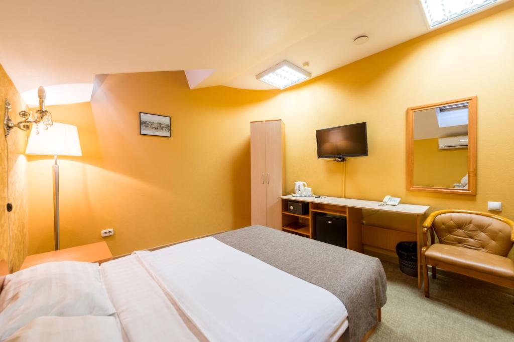 1 dormitorio con cama, escritorio y espejo en Hotel Menshikov, en Ulan-Ude