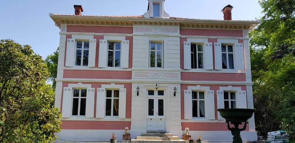 a red and white building with a fountain in front of it at Manoir de Tireveste in Lesperon