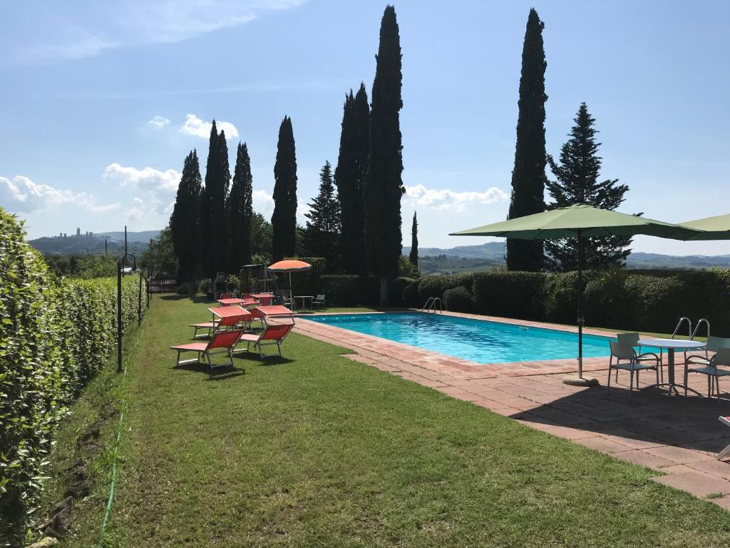 a pool with chairs and a table and an umbrella at Podere Remignoli in San Gimignano