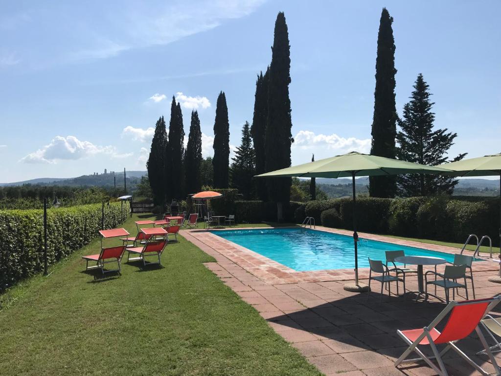 a pool with chairs and tables and umbrellas at Podere Remignoli in San Gimignano