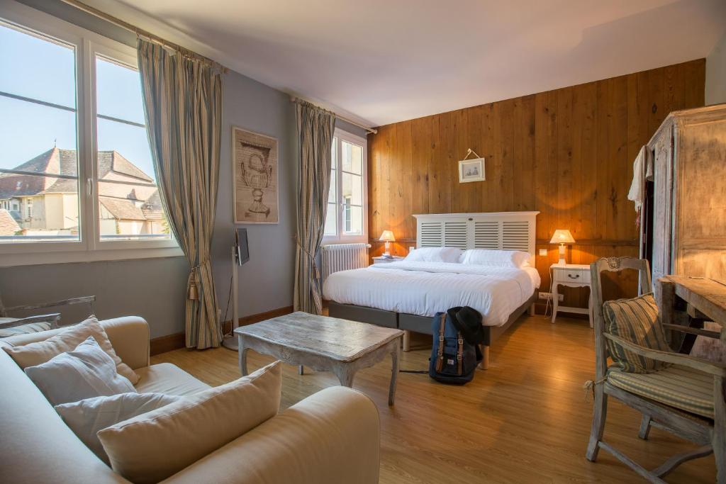 a hotel room with two beds and a couch at Logis Hôtel Le Beaulieu in Beaulieu-sur-Dordogne