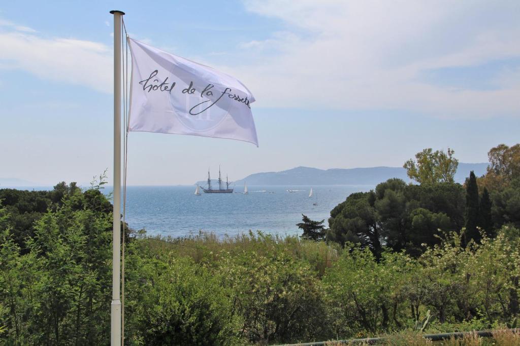 Biała flaga ze statkiem w wodzie w obiekcie Hôtel de La Fossette w mieście Le Lavandou