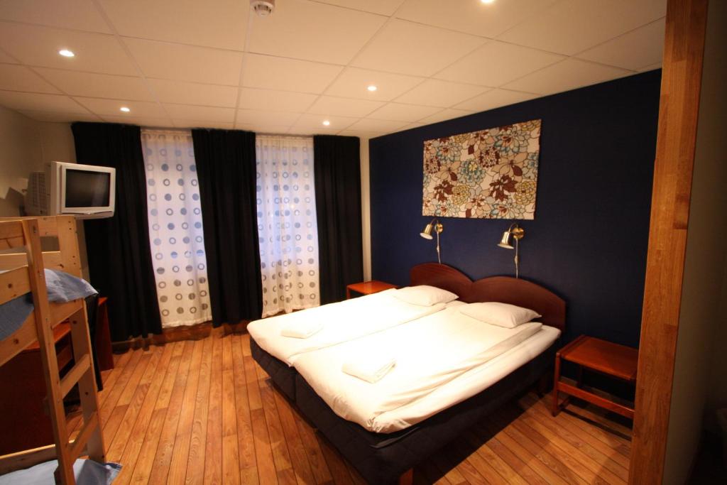 a bedroom with a bed with white sheets at Hotell Linnéa in Ljungby