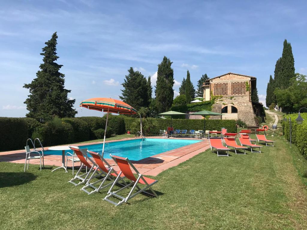 a pool with chairs and an umbrella next to a house at Podere Remignoli in San Gimignano