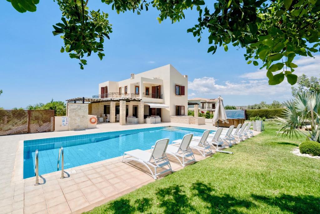 een villa met een zwembad en ligstoelen bij 5 bedroom Villa Poseidon with private pool, Aphrodite Hills Resort in Kouklia