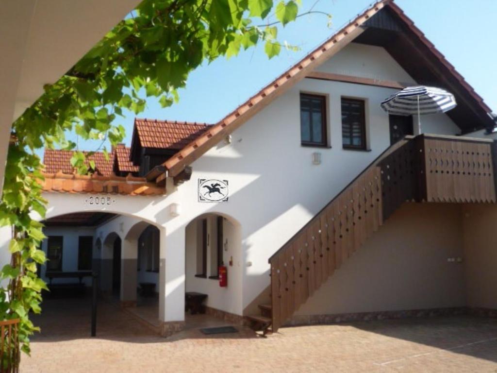 a white house with a staircase and an umbrella at Pension Černý jezdec in Lednice