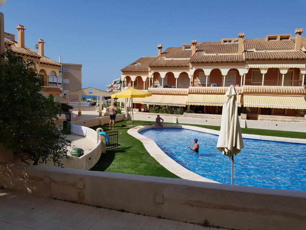 a swimming pool with an umbrella and people in the water at Retiro de Levante in Santa Pola