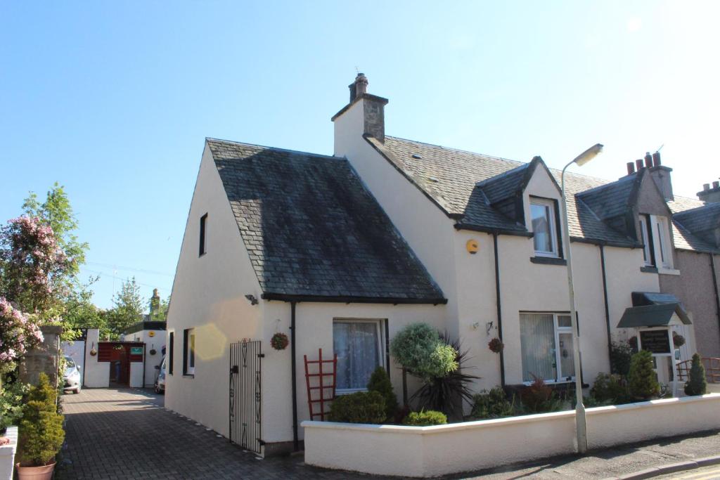 una casa blanca con techo negro en una calle en Pitfaranne Guest House, en Inverness