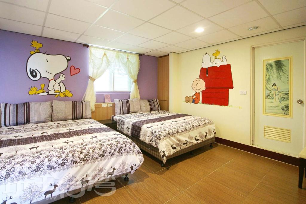 a bedroom with two beds and a wall with cartoons on it at Her Home Homestay in Green Island
