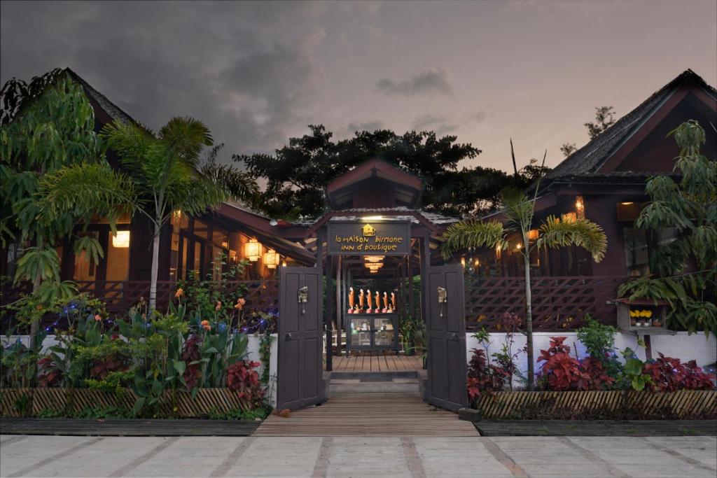 a house with a gate and flowers in front of it at La Maison Birmane Boutique Hotel in Nyaung Shwe
