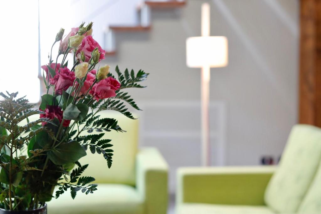 um vaso com flores em frente a um sofá verde em Castelli Delux em Menaggio