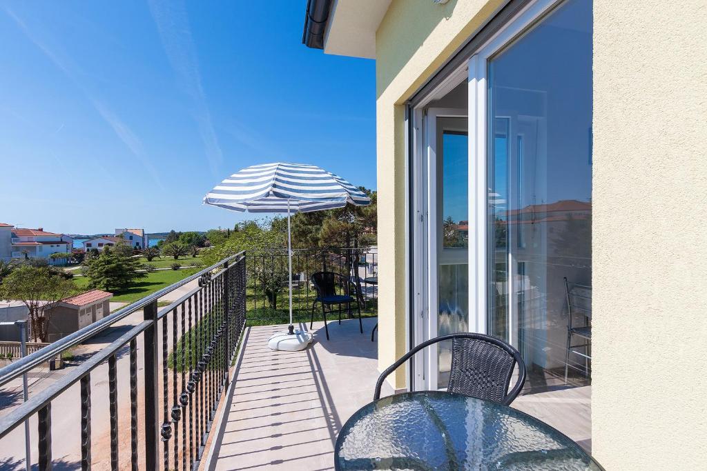 a balcony with a table and an umbrella at Guesthouse Bencun Medulin in Medulin