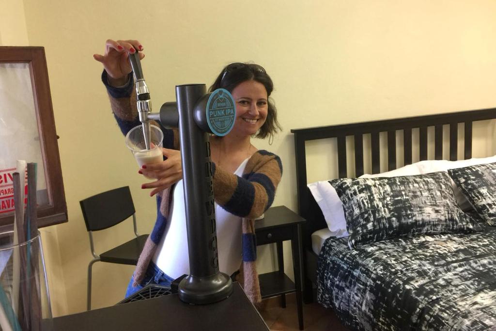 a woman is holding a wine glass in a room at La Sosta Navarra Bed & Beer in Gubbio