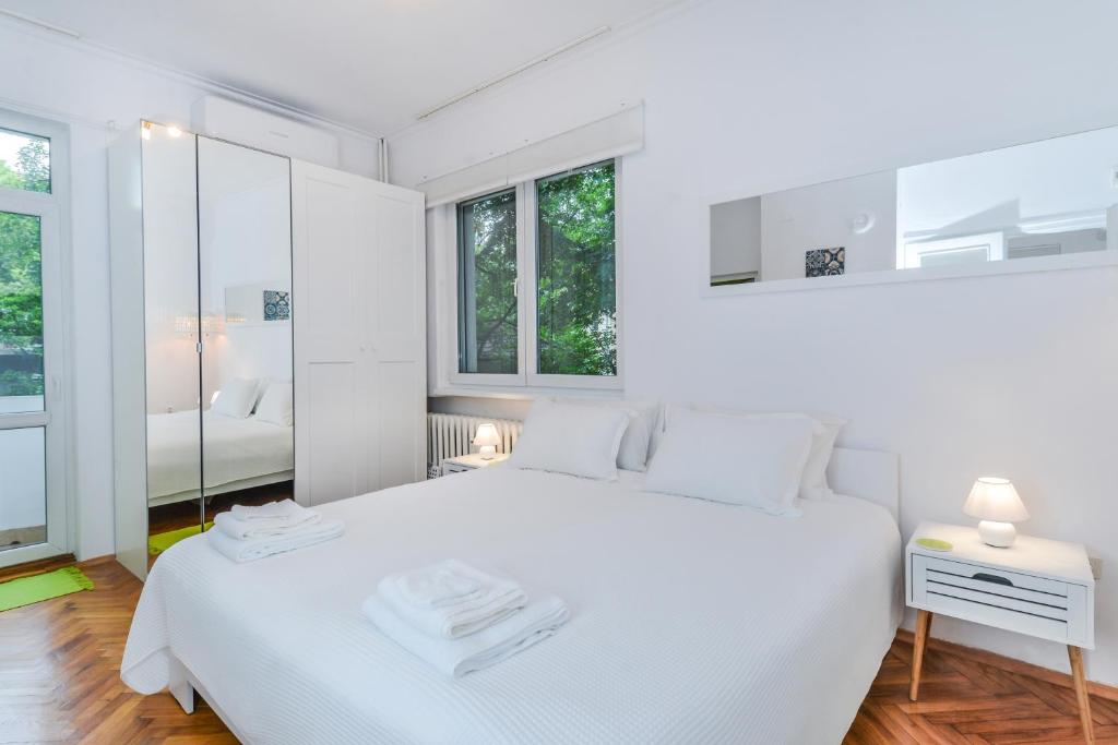 - une chambre blanche avec un grand lit blanc et des fenêtres dans l'établissement The Charming Home - One Bedroom TOP Central Apartment, à Sofia
