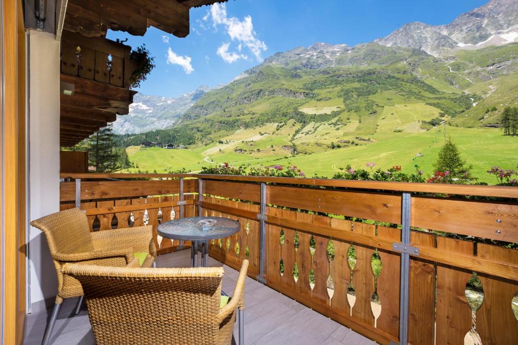 uma mesa e cadeiras numa varanda com vista para as montanhas em Hotel Restaurant Rosmarie em Pfelders