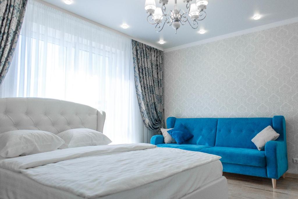 a bedroom with a bed and a blue couch at Apartment Status in Kaliningrad