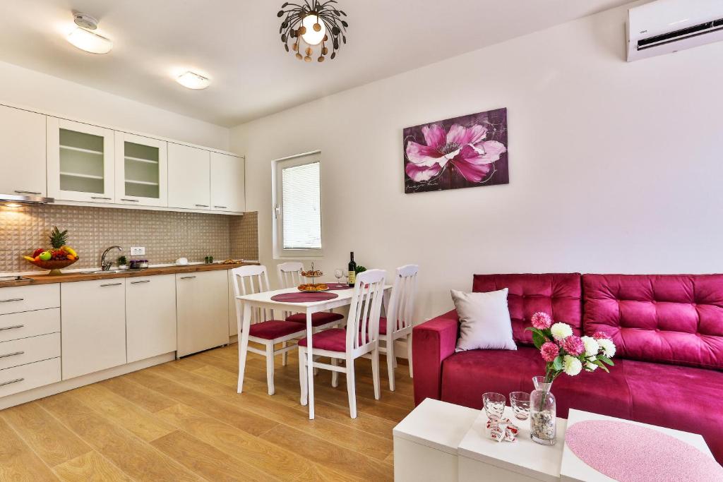 a kitchen and a living room with a red couch at Apartments Royal Lux in Sutomore