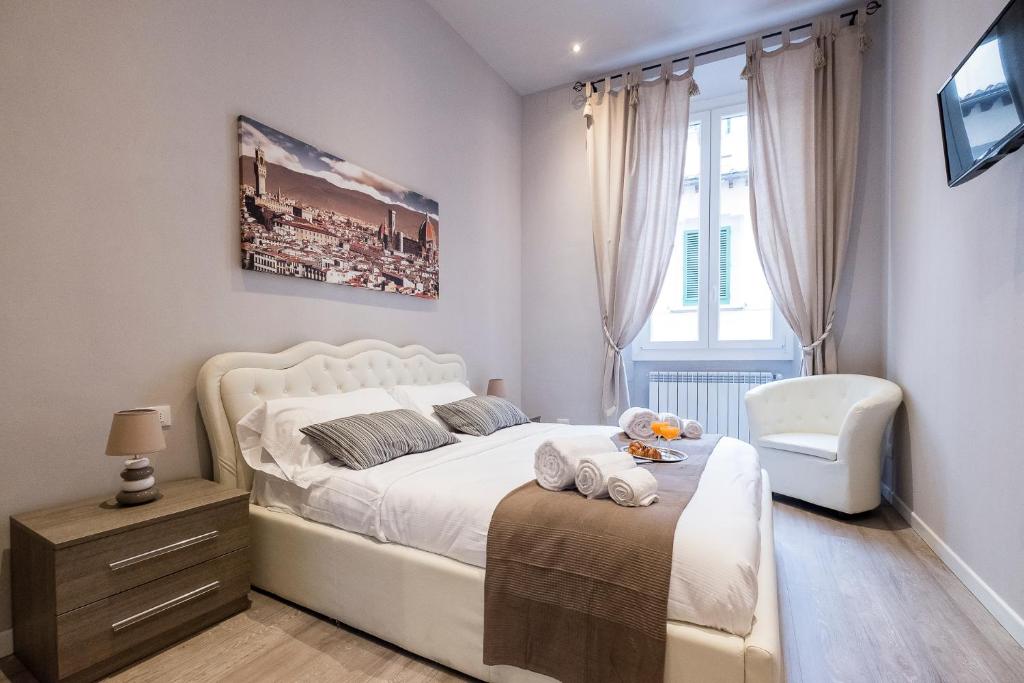 sypialnia z białym łóżkiem i krzesłem w obiekcie Silver Novella Luxury Apartment - Centro Storico we Florencji