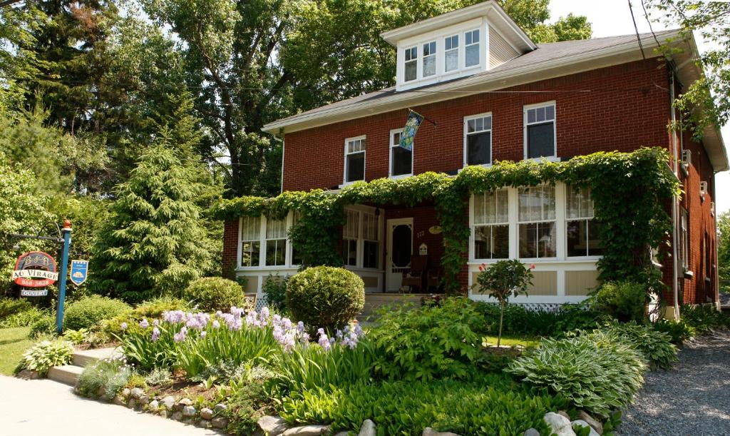 a red brick house with flowers in the front yard at Au Virage B&B in Magog-Orford