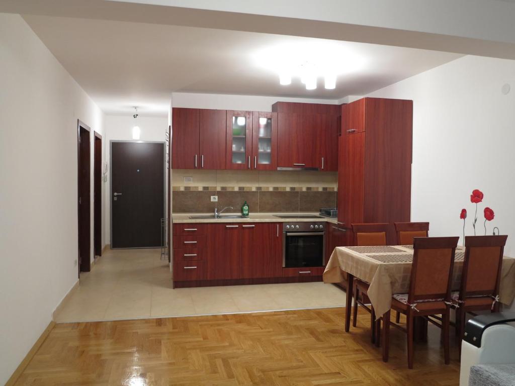 uma cozinha com armários de madeira e uma mesa com uma sala de jantar em Apartment Sunrise em Sveti Stefan