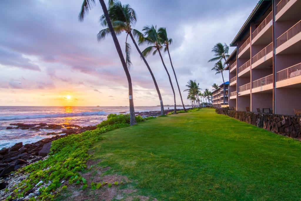 a resort with palm trees and the ocean at sunset at Kona Reef Hawaii by Raintree in Kailua-Kona