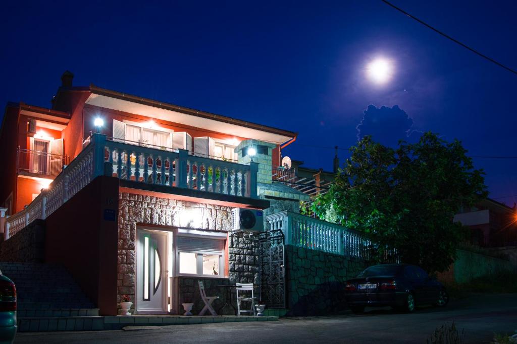 Una casa de noche con la luna detrás. en Apartment Laura en Senj