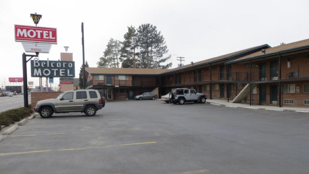 a motel with two cars parked in a parking lot at Belcaro Motel in Denver