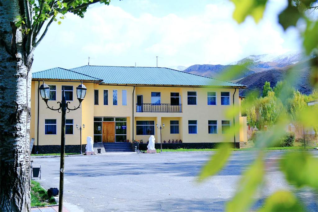 un grande edificio giallo con un lampione davanti di Khan Tengri Hotel a Naryn