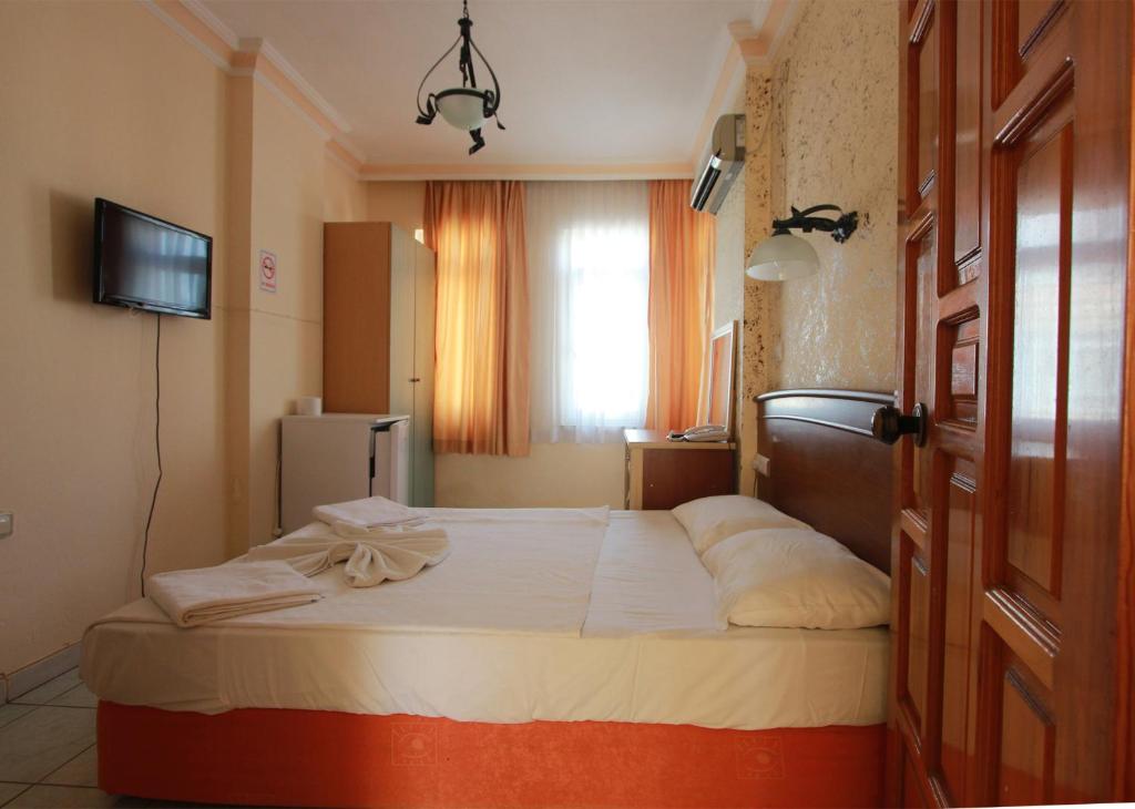 Cama en habitación con TV y ventana en Damlatas Elegant Apart Hotel, en Alanya