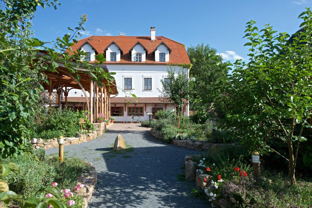 a large white house with a pathway in a garden at Babiččina Zahrada Penzion & Restaurant in Prŭhonice