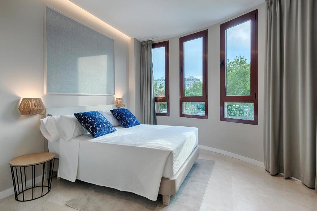 a bedroom with a white bed with blue pillows at Opera House Valencia B&B in Valencia