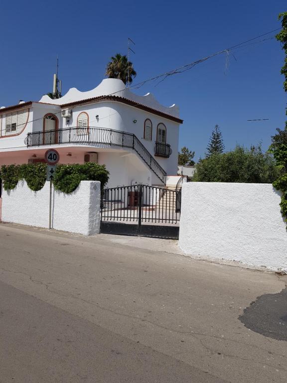 a white house with a balcony on a street at DesyMar Inn in Fontane Bianche