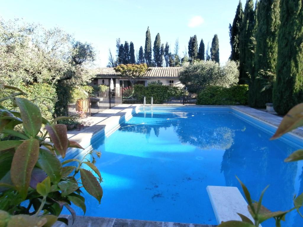 a swimming pool with blue water in a yard at Les grands pins in Saint-Andiol