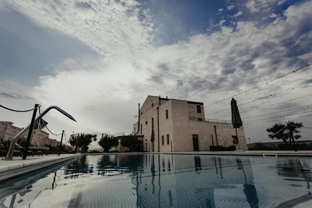 an empty swimming pool in front of a building at Masseria Sacramento in Palagianello